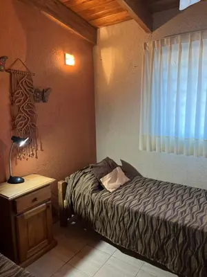 a bedroom with a bed and a lamp on a table at Complejo de Cabañas Aires de Santiago in San Antonio de Arredondo