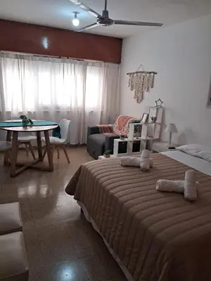 a bedroom with two beds and a table and a couch at Monoambiente Centro villa Carlos Paz in Villa Carlos Paz