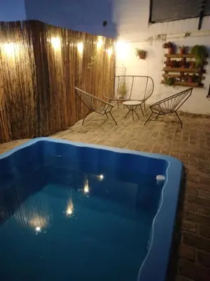 a blue swimming pool with two chairs and a table at Departamento La Cuesta in Villa Carlos Paz