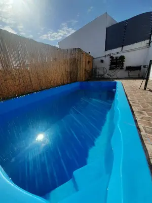 a large blue swimming pool next to a building at Departamento La Cuesta in Villa Carlos Paz