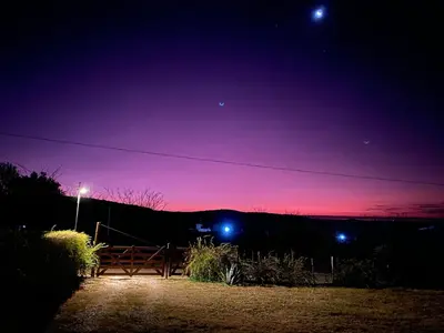 a night sky with a bench and lights in a field at Nuestro lugar en Traslasierra in Los Hornillos