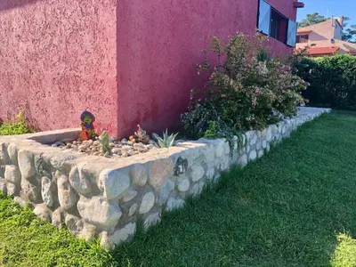 a stone retaining wall with a garden in front of a house at Nuestro lugar en Traslasierra in Los Hornillos