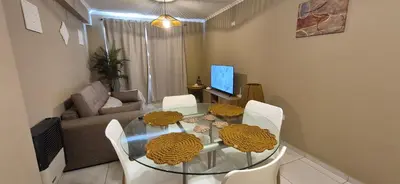 a dining room with a glass table and white chairs at Departamento en Complejo Villa Sol in Cordoba