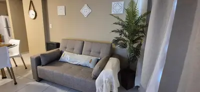 a living room with a couch and a plant at Departamento en Complejo Villa Sol in Cordoba