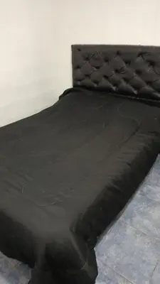 a bed with a black comforter on top of it at Violeta in Cordoba