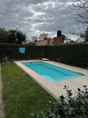 a swimming pool in a yard next to a hedge at Departamento Carlos Paz in Villa Carlos Paz