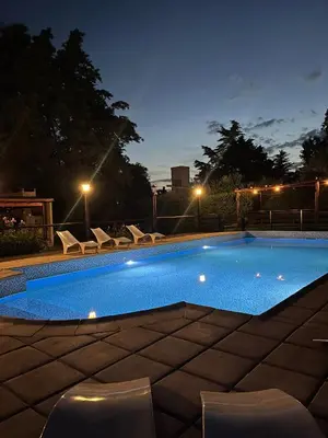 a swimming pool with chairs around it at night at Apart Morena in Villa Rumipal