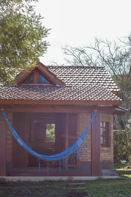 a house with a blue hammock hanging from it at cabañas Samay-Piskho in Santa Rosa de Calamuchita