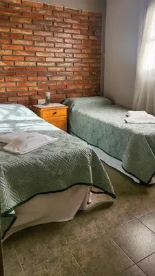 a room with two beds and a brick wall at cabañas Samay-Piskho in Santa Rosa de Calamuchita