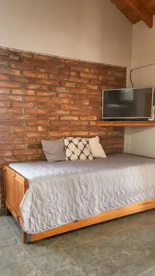 a bed in a room with a wall with a television at cabañas Samay-Piskho in Santa Rosa de Calamuchita