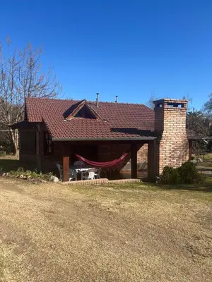 a brick house with a red roof on a yard at cabañas Samay-Piskho in Santa Rosa de Calamuchita