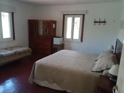 a bedroom with a bed and a dresser and two windows at Estancia Santa María de las Casas Viejas in Mina Clavero
