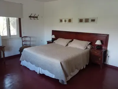 a bedroom with a large bed and a chair at Estancia Santa María de las Casas Viejas in Mina Clavero