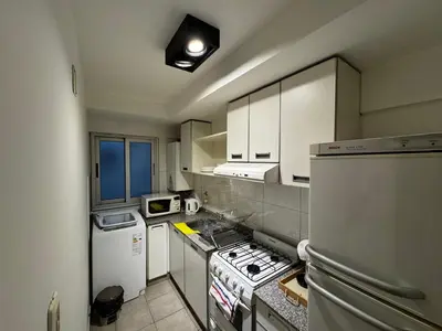 a small kitchen with white cabinets and a refrigerator at Modern apartment - Nueva Córdoba in Cordoba