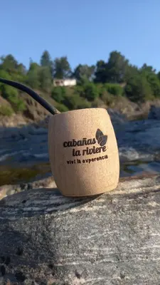 a cup of coffee sitting on a rock next to a river at la riviere in Alta Gracia