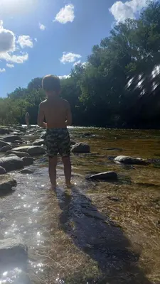a young boy standing in the water on a beach at la riviere in Alta Gracia