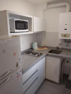 a small kitchen with white cabinets and a microwave at Chacabuco 275 By Suviex in Cordoba