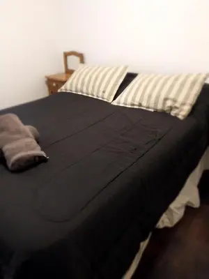 a bed with a black blanket on top of it at Chacabuco 275 By Suviex in Cordoba