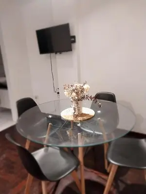 a glass table with chairs and a vase of flowers at Chacabuco 275 By Suviex in Cordoba