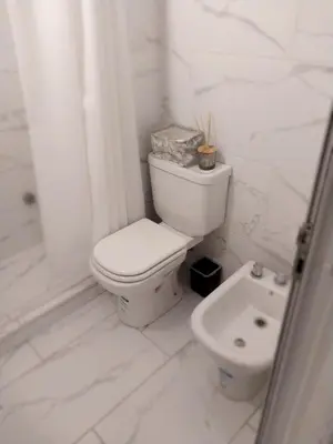 a white bathroom with a toilet and a sink at Chacabuco 275 By Suviex in Cordoba