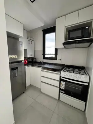 a white kitchen with a stove and a microwave at Avellaneda Homestay in Cordoba