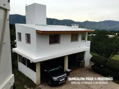 a white house with a car parked in the garage at Complejo BIALET MASSE in Bialet Massé