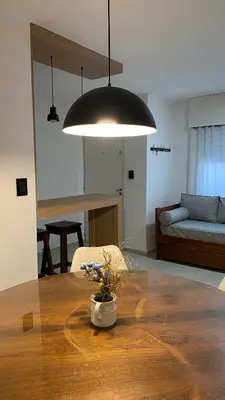 a living room with a wooden table and a large light fixture at Departamento Plaza Colón in Cordoba