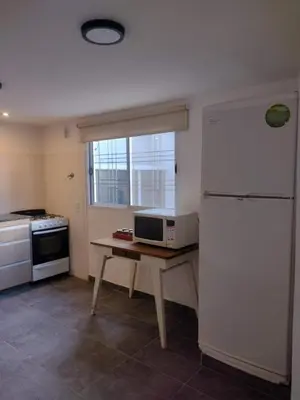 a kitchen with a refrigerator and a table with a microwave at Tierra Madre in Santa Rosa de Calamuchita