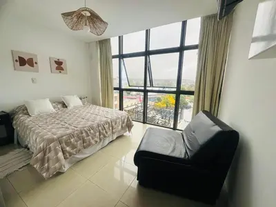 a bedroom with a bed and a chair and a large window at Edificio Melos Villa Carlos Paz in Villa Carlos Paz
