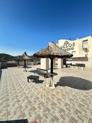 a patio with benches and umbrellas in front of a building at Edificio Melos Villa Carlos Paz in Villa Carlos Paz