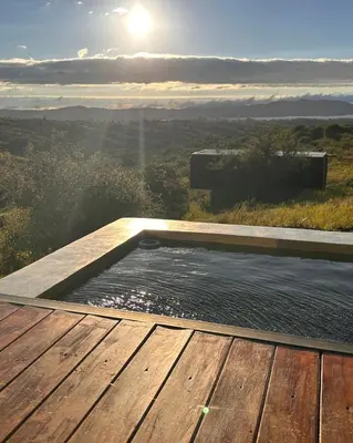 a hot tub on a deck with the sun in the background at Suite del Alba in La Estancia