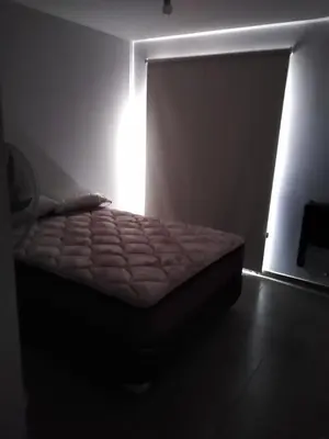 a bed in a dark room with a window at Departamento céntrico amplio in Río Cuarto