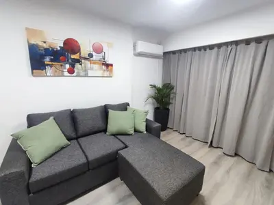 a living room with a gray couch and a window at Apartamento Los Capuchinos in Cordoba