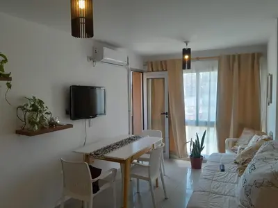 a living room with a table and a tv on a wall at Hermoso Departamento en Güemes sobre Cañada in Cordoba