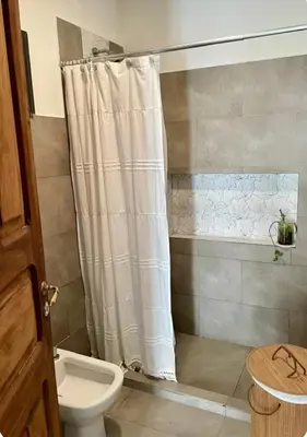 a bathroom with a shower curtain and a toilet at Casa de huésped in Río Tercero