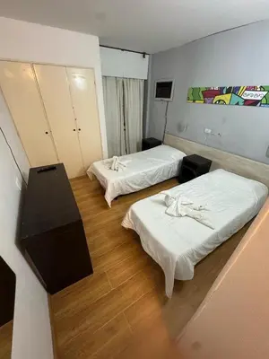 a room with two beds and a desk in it at Hotel Nuevo Uruguay in Villa Carlos Paz