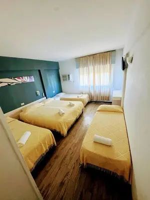 a hotel room with three beds with yellow covers at Hotel Nuevo Uruguay in Villa Carlos Paz