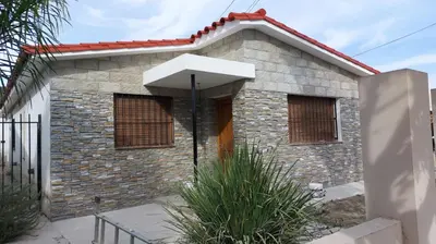 a small brick house with an umbrella in front of it at Casa a 800 mts de pleno centro - NO RECIBO GRUPO DE JOVENES in Villa Carlos Paz