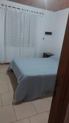 a bed in a room with a window with a white bedspread at Abuelo José Cabaña Serrana in Villa Yacanto