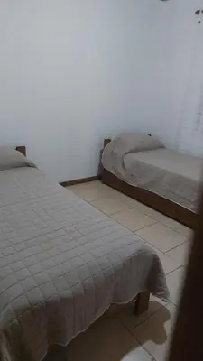 two twin beds in a bedroom with a tiled floor at Abuelo José Cabaña Serrana in Villa Yacanto