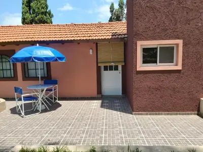 a house with a table and a blue umbrella at Ipomeas in Villa Rumipal