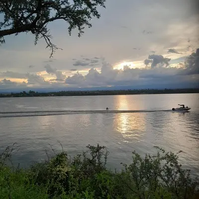a boat on a lake with the sun setting at Ipomeas in Villa Rumipal