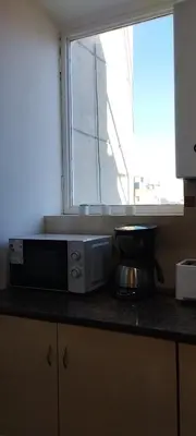 a kitchen with a microwave on a counter with a window at Waru - Vista increíble y ubicación ideal in Cordoba