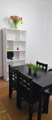 a black dining room table with two chairs and flowers at Departamento funcional in Villa Carlos Paz