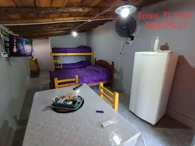 a room with a table and a bed and a refrigerator at El Carpo in Santa Rosa de Calamuchita
