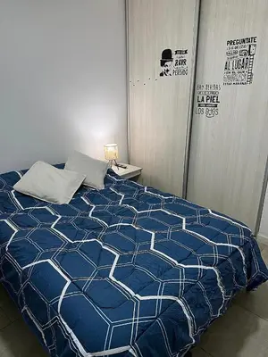 a bed with a blue and white comforter in a room at Nueva Córdoba Ejecutivo in Cordoba