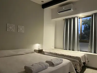 a white bedroom with two beds and a window at Olmos Suites in Mina Clavero