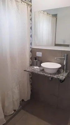 a bathroom with a white sink and a mirror at Olmos Suites in Mina Clavero