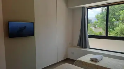 a room with a tv on the wall and a window at Olmos Suites in Mina Clavero