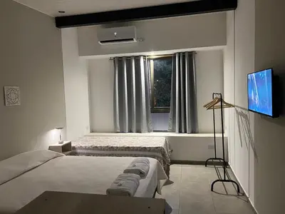 a bedroom with two beds and a tv and a window at Olmos Suites in Mina Clavero